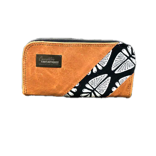 Un portefeuille fabriqué à partir de cuir caramel et d'un coupon d'écharpe de portage en noir et blanc au motif géométrique inspiré par la nature à l'extérieur, et de popeline noire à l'intérieur.