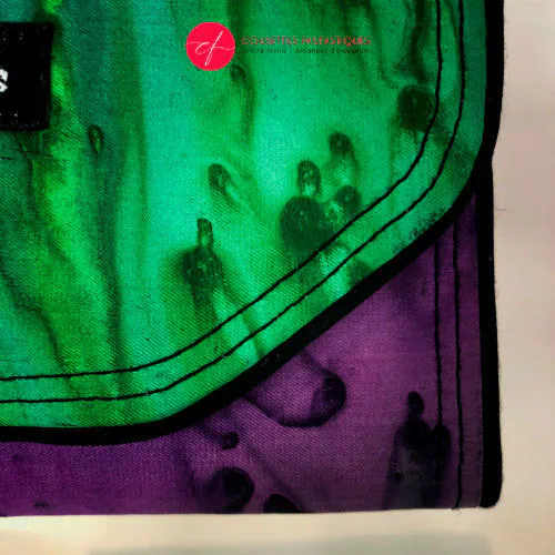 Un portefeuille fait en voile de soie bleu, vert et violet associé à du cuir d'agneau noir à l'extérieur, et en popeline taupe à l'intérieur.