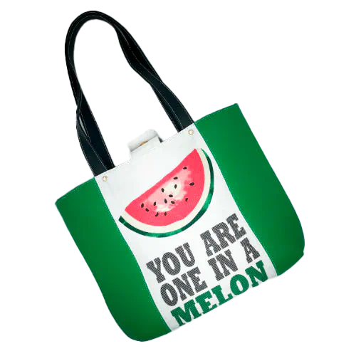 Un grand sac fait à l'extérieur de cuir vert et d'une toile imprimée d'un dessin de fruit avec un jeu de mots en anglais dessous, et à l'intérieur d'une popeline vert forêt.