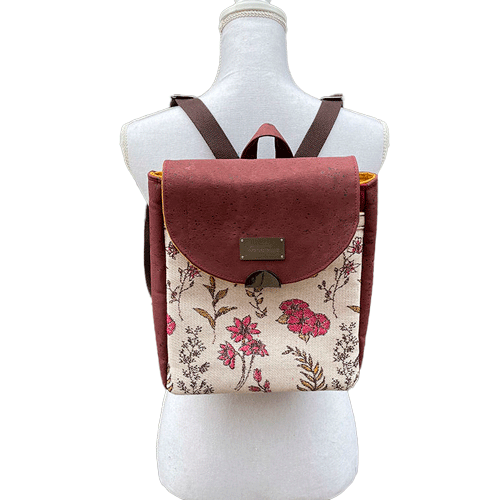 Un sac à dos fabriqué avec un tissu d'écharpe à motifs floraux dans des tons roses sur fond écru et en liège couleur brique.