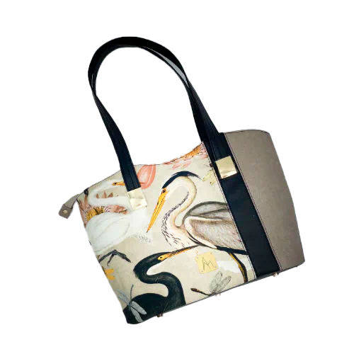 Un grand sac d'épaule type cabas zippé, fabriqué à partir d'un tissu épais au motif d'oiseaux sauvages associé à des simili noir et taupe, et une doublure lin crème chiné et corail.