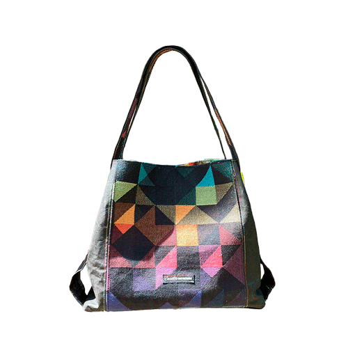 Un sac d'épaule fabriqué avec une écharpe de portage noire à motif géométrique arc-en-ciel et du liège noir, avec un intérieur en tourbillon arc-en-ciel lumineux.