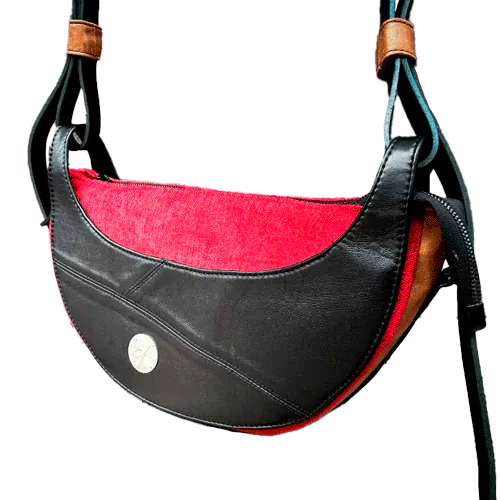 Un sac à bandoulière en cuir noir et caramel, tissu d'ameublement en velours rouge et noir, et satins rouge et noir.