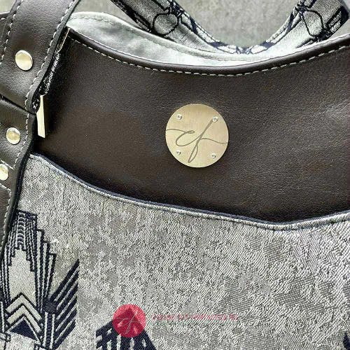 Un sac d'épaule fait avec du tissu d'écharpe bleu nuit et argenté au motif géométrique art déco, et du cuir bleu nuit.