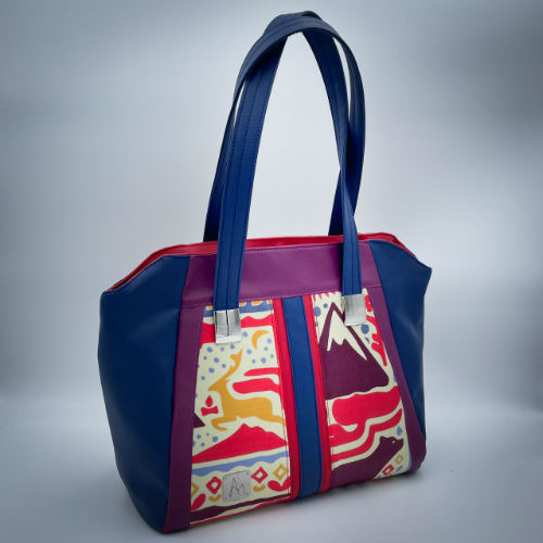 Un sac d'épaule fabriqué à partir d'un foulard en soie avec des motifs issus du folklore Scandinave, associé à des similis rouge, bleu et violet.