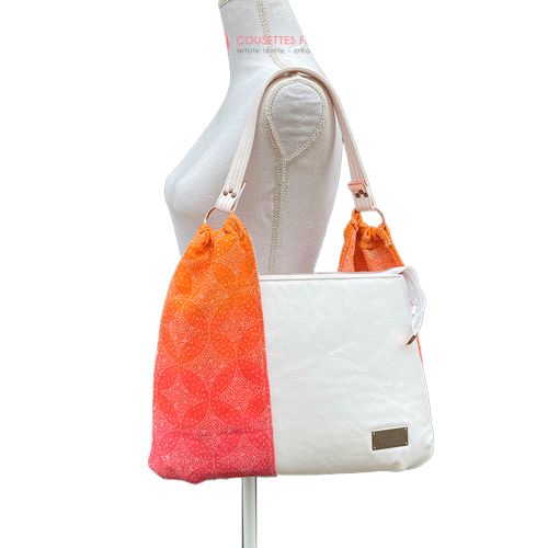 Un sac d'épaule fait avec du tissu d'écharpe dégradé de jaune orangé à rose, au motif motif étoiles pointillistes, et du simili blanc.