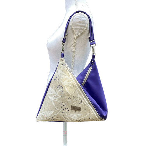 Un sac d'épaule triangulaire en simili beige et tissu d'écharpe de portage blanc, crème, beige et vert.