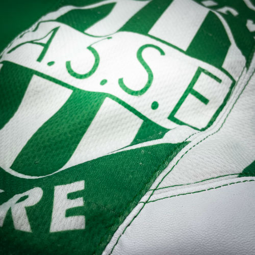 Un sac d'épaule en cuirs blanc et vert associés à un maillot de foot vintage vert et blanc, et une doublure en satin de polyester blanc et vert.
