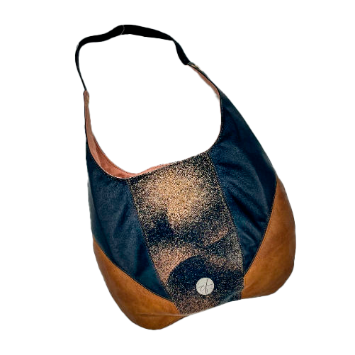 Un sac d'épaule en cuirs marron et noir, écharpe de portage noir, marron et beige avec un motif abstrait rond, et toile de lin pêche.