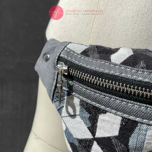 Une banane en tissu d'écharpe de portage aux tons gris, blanc et bleu avec un motif floral et géométrique et en denim gris.
