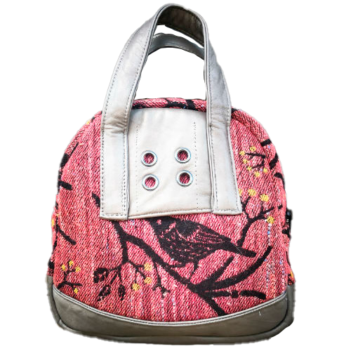 Un mini sac à main fabriqué à partir de chutes d'écharpe de portage montrant des oiseaux dans un arbre dans des tons roses et noirs, et du cuir d'agneau gris.