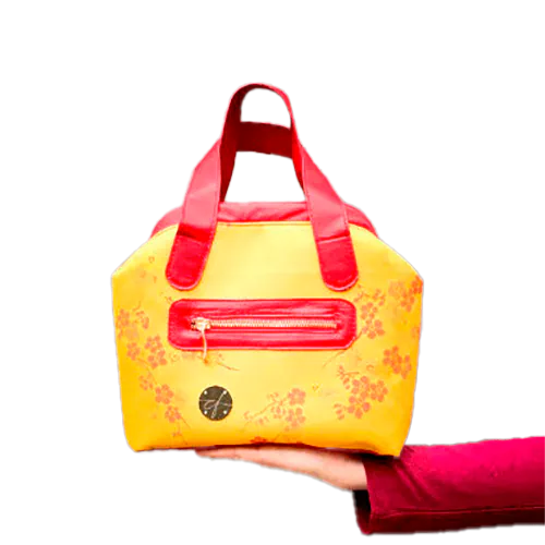 Un mini sac à main constitué de tissu d'ameublement jaune motif fleurs de cerisier rouge et de cuir rouge.