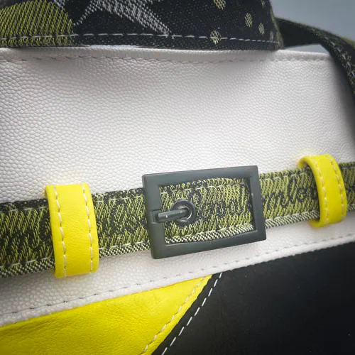 Un sac long et peu haut confectionné avec des cuirs jaune, blanc et noir et un coupon d'écharpe de portage au motif floral en noir, jaune et blanc, avec une doublure de toile jaune.