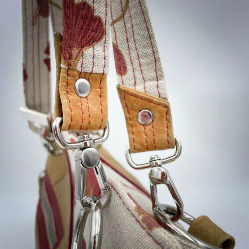 Un sac à main fait d'un cuir de couleur camel et une toile en polycoton avec un motif de feuilles de Ginkgo Biloba rouges.