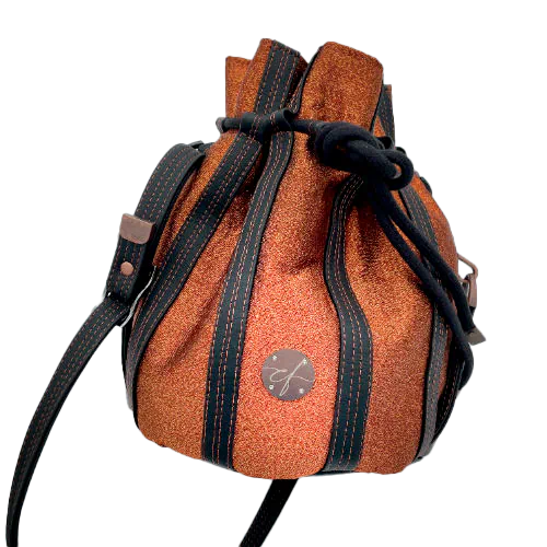 Un sac seau brillant fabriqué avec un tissu lamé bronze brillant et du simili noir mat et doux.