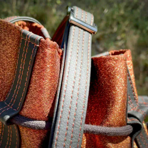 Un sac seau brillant fabriqué avec un tissu lamé bronze brillant et du simili noir mat et doux.