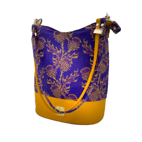 Un sac seau fabriqué avec de l'écharpe de portage au motif de chardons jaunes sur fond violet et du cuir d'agneau jaune.
