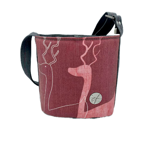 Un petit sac dit “seau” fait avec toile fine rose présentant deux silhouettes de cerfs blanches, et du denim haute-couture gris.