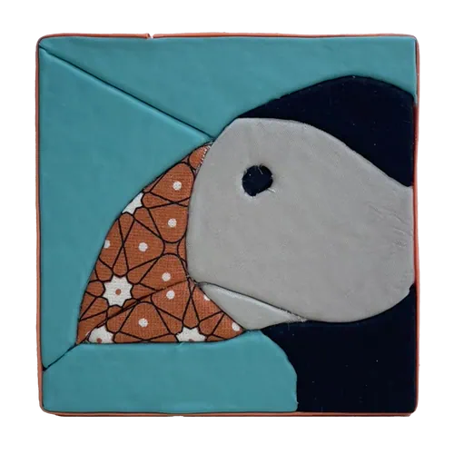 Tableau textile Kinusaiga de 10 × 10 cm représentant une tête de macareux de profil : tête gris clair, œil et calotte noirs, bec en cretonne orange à motif géométrique, sur fond turquoise, bordé d'un biais orange.