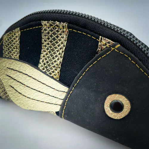 Une pochette zippée cousue dans du liège noir, du voile noir avec des bandes dorées et du cuir métallisé doré.