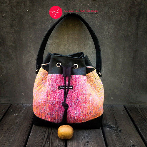 A shoulder bag made from mirror gradient woven wrap in pink to blue and black cork.