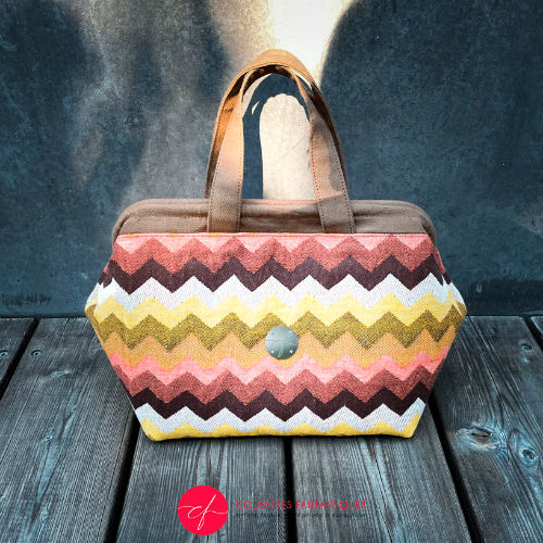 A handbag made of wrap fabric with a giant chevron pattern in autumn tones (pink, brown, orange, yellow, and white).