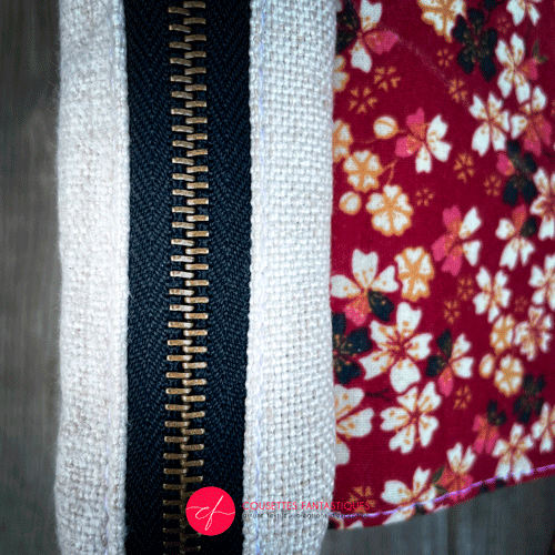 A fanny pack made from coarse ecru canvas with a black geometric pattern of plus signs and a flowery poplin in red, black, white, and yellow tones.