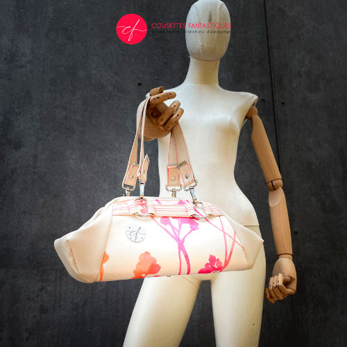 A small handbag made of cream synthetic upholstery fabric with a botanical pattern that fades from pink to orange.