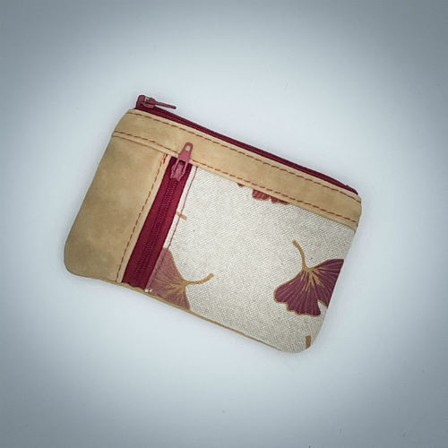 A mini zippered coin purse made of camel colored leather and a red Ginkgo Biloba leaves patterned polycotton canvas.