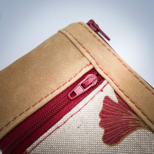 A mini zippered coin purse made of camel colored leather and a red Ginkgo Biloba leaves patterned polycotton canvas.