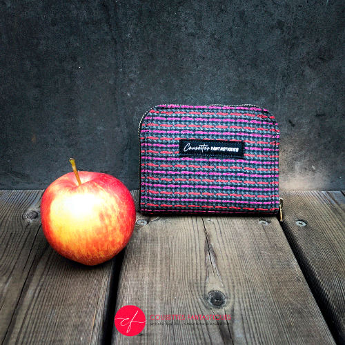 A small zippered card and coin holder made of gray fabric embroidered with shiny pink and red lines, with a textured gray matte interior.