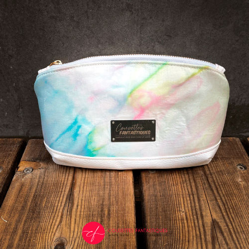 A small zippered pouch made of white faux leather and a hand-painted silk scarf.