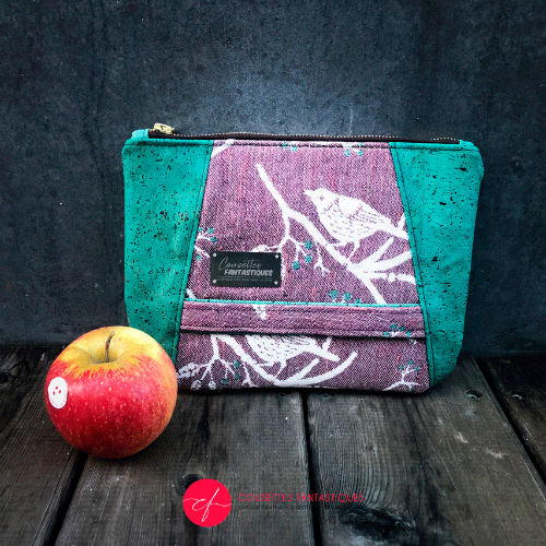 A zippered pouch sewn from a mauve and green babywearing wrap with a bird motif on branches, combined with emerald green cork.