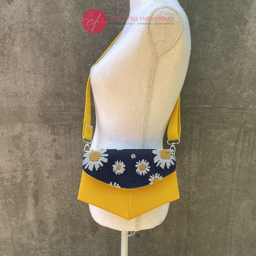 A small bag made from yellow faux leather and a fabric coupon with white and yellow daisies on a navy blue background.