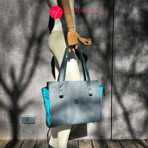 A shoulder bag made of turquoise babywearing fabric with hummingbird and petal motifs, combined with gray and turquoise imitation leather.