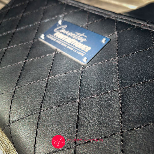 A zippered card and coin holder made with hand-quilted black faux leather on the outside, and cotton canvas with sequins on the inside.